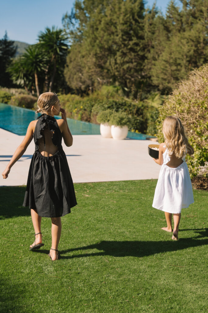 Young girls wearing Freya Lillie frilled linen dresses in Ibiza headed for the swimming pool