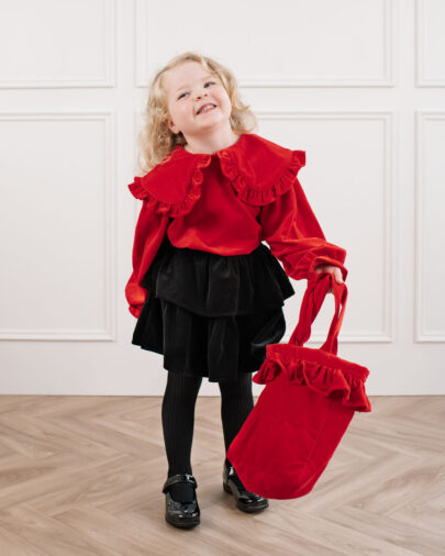 A toddler girl dressed in christmas velvets carrying her red velvet pretty tote bag